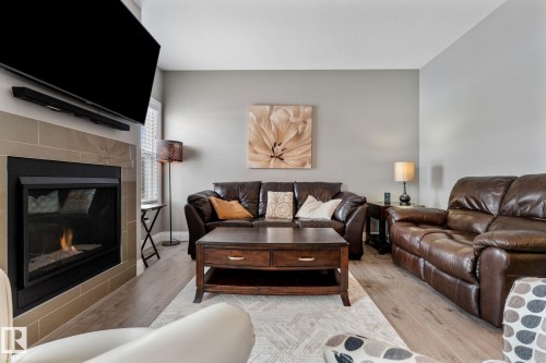 Living room featuring a tile fireplace and light wood-type flooring - 1043 South Creek Wynd, Stony Plain, AB - Indoor Photo Showing Living Room With Fireplace