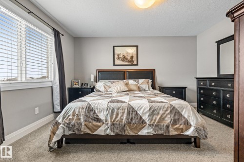 Carpeted bedroom featuring baseboards and a textured ceiling - 1043 South Creek Wynd, Stony Plain, AB - Indoor Photo Showing Bedroom