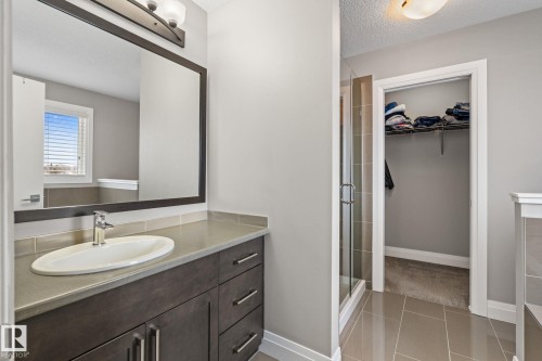 Bathroom with a spacious closet, vanity, a textured ceiling, a shower stall, and light tile patterned floors - 1043 South Creek Wynd, Stony Plain, AB - Indoor Photo Showing Bathroom