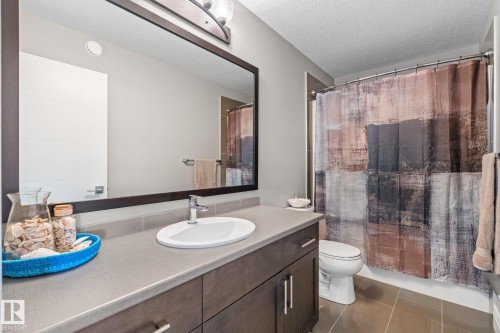 Bathroom featuring vanity, dark tile patterned floors, a textured ceiling, and shower / bath combo with shower curtain - 1043 South Creek Wynd, Stony Plain, AB - Indoor Photo Showing Bathroom