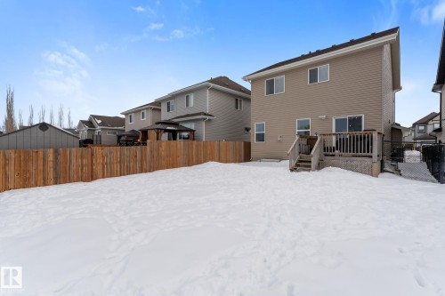Snow covered rear of property featuring a fenced backyard, a wooden deck, and a residential view - 1043 South Creek Wynd, Stony Plain, AB - Outdoor With Exterior
