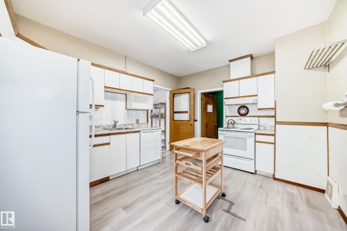 Kitchen featuring white appliances, two tone cabinetry, light countertops, light wood-style flooring, and decorative backsplash - 9823 75 Avenue, Edmonton, AB - Indoor Photo Showing Kitchen