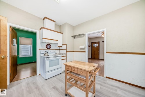 Kitchen featuring electric range, light countertops, dual tone cabinets, and light wood-type flooring - 9823 75 Avenue, Edmonton, AB - Indoor Photo Showing Kitchen