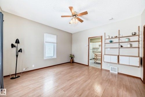 Unfurnished bedroom featuring light wood-style flooring, ceiling fan, and freestanding refrigerator - 9823 75 Avenue, Edmonton, AB - Indoor Photo Showing Other Room