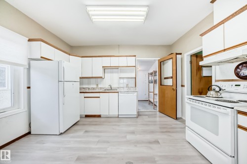 Kitchen featuring white appliances, light countertops, dual tone cabinetry, and light wood-style floors - 9823 75 Avenue, Edmonton, AB - Indoor Photo Showing Kitchen