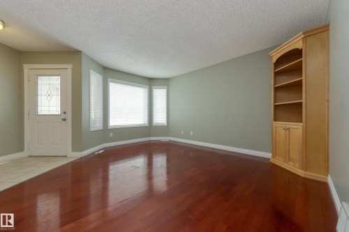 Unfurnished living room with a textured ceiling, dark wood finished floors, and built in shelves - 9916 178 Avenue, Edmonton, AB - Indoor Photo Showing Other Room