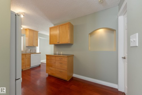 Kitchen with white appliances, dark wood-style floors, light wood finish cabinetry, a textured ceiling, and light countertops - 9916 178 Avenue, Edmonton, AB - Indoor Photo Showing Kitchen