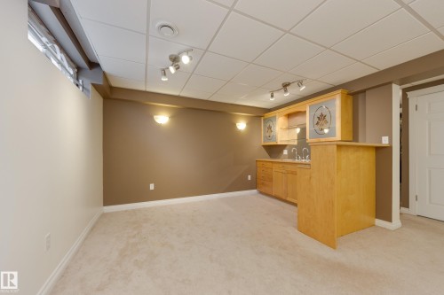 Indoor wet bar featuring light wood finish cabinetry, light carpet, rail lighting, a paneled ceiling, and light countertops - 9916 178 Avenue, Edmonton, AB - Indoor Photo Showing Other Room