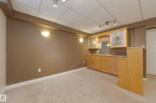 Kitchen featuring light wood finish cabinetry, a paneled ceiling, light countertops, light carpet, and glass fronted cabinets - 9916 178 Avenue, Edmonton, AB - Indoor Photo Showing Other Room