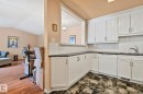 Kitchen with white dishwasher, decorative backsplash, white cabinetry, vaulted ceiling, and dark stone countertops - 313 Willow Court, Edmonton, AB  - Indoor Photo Showing Kitchen 