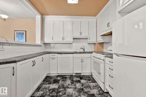 Kitchen featuring white appliances, white cabinets, backsplash, and dark stone counters - 313 Willow Court, Edmonton, AB - Indoor Photo Showing Kitchen