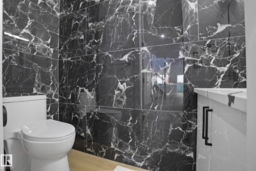 Full bath featuring a marble finish shower and wood finished floors - 15415 20 Street, Edmonton, AB - Indoor Photo Showing Bathroom