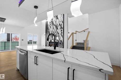 Kitchen featuring dark wood-style floors, white cabinetry, light stone countertops, dishwasher, and an island with sink - 15415 20 Street, Edmonton, AB - Indoor Photo Showing Kitchen With Double Sink With Upgraded Kitchen