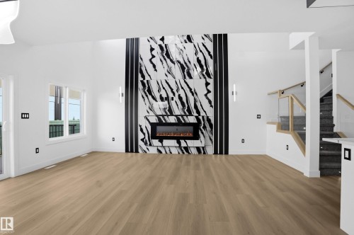 Unfurnished living room featuring light wood-style floors and a fireplace - 15415 20 Street, Edmonton, AB - Indoor With Fireplace