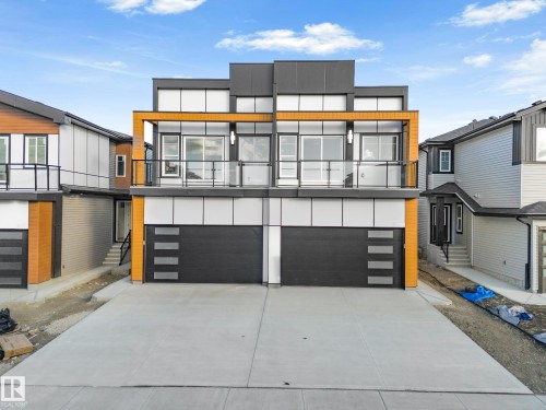 Contemporary house featuring a garage, concrete driveway, board and batten siding, and a balcony - 15415 20 Street, Edmonton, AB - Outdoor