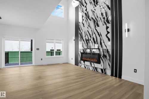 Unfurnished living room featuring a high ceiling, wood finished floors, and a large fireplace - 15415 20 Street, Edmonton, AB - Indoor With Fireplace
