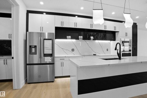 Kitchen featuring stainless steel appliances, white cabinetry, light wood finished floors, and light stone countertops - 15415 20 Street, Edmonton, AB - Indoor Photo Showing Kitchen With Upgraded Kitchen