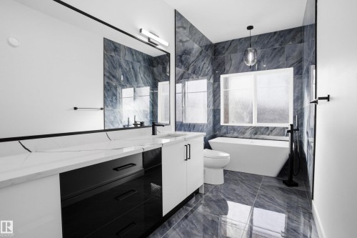 Bathroom featuring vanity, a soaking tub, plenty of natural light, and dark marble finish flooring - 15415 20 Street, Edmonton, AB - Indoor Photo Showing Bathroom