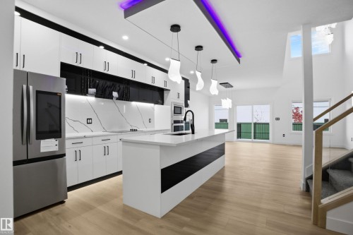 Kitchen featuring white cabinetry, stainless steel appliances, an island with sink, hanging light fixtures, and a high ceiling - 15415 20 Street, Edmonton, AB - Indoor Photo Showing Kitchen With Upgraded Kitchen