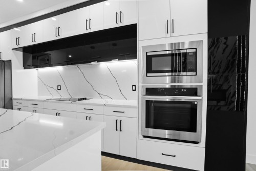 Kitchen featuring white cabinetry, stainless steel appliances, light stone countertops, and light wood-type flooring - 15415 20 Street, Edmonton, AB - Indoor Photo Showing Kitchen