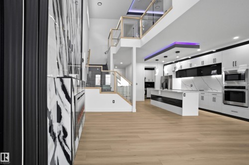 Kitchen featuring white cabinetry, stainless steel appliances, a center island, decorative light fixtures, and light wood-type flooring - 15415 20 Street, Edmonton, AB - Indoor Photo Showing Kitchen