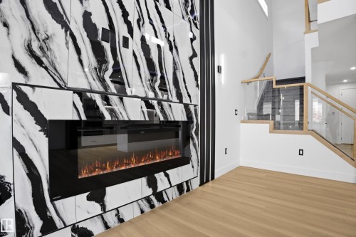 Stairs featuring a glass covered fireplace and wood finished floors - 15415 20 Street, Edmonton, AB - Indoor Photo Showing Other Room With Fireplace