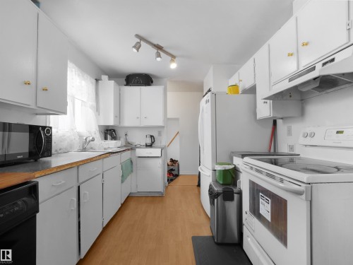 Kitchen featuring white appliances, white cabinetry, light wood-style flooring, and track lighting - 17122 96 Street, Edmonton, AB - Indoor Photo Showing Kitchen