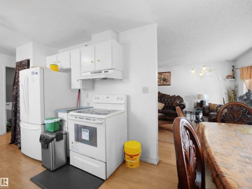 Kitchen featuring white appliances, white cabinetry, light wood-style flooring, a chandelier, and a textured ceiling - 17122 96 Street, Edmonton, AB - Indoor Photo Showing Kitchen