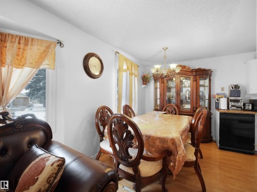 Dining area with a chandelier, light wood-style floors, a textured ceiling, and healthy amount of natural light - 17122 96 Street, Edmonton, AB - Indoor Photo Showing Dining Room