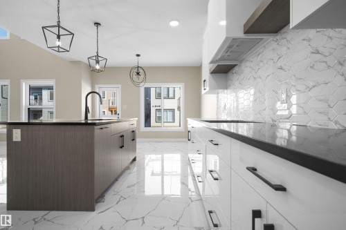 Kitchen with modern cabinets, a kitchen island with sink, dark stone counters, and hanging light fixtures - 3910 41 Avenue, Beaumont, AB - Indoor Photo Showing Kitchen