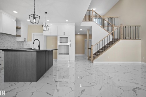 Kitchen with a center island with sink, dual tone cabinets, tasteful backsplash, light marble finish floors, and decorative light fixtures - 3910 41 Avenue, Beaumont, AB - Indoor Photo Showing Kitchen With Upgraded Kitchen