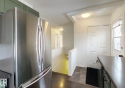 Kitchen featuring stainless steel appliances, dark countertops, dark wood-style flooring, and green cabinets - 