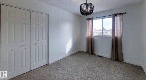 Unfurnished bedroom with hanging lights, a closet, and light carpet - 1102 55 Street, Edson, AB - Indoor Photo Showing Other Room