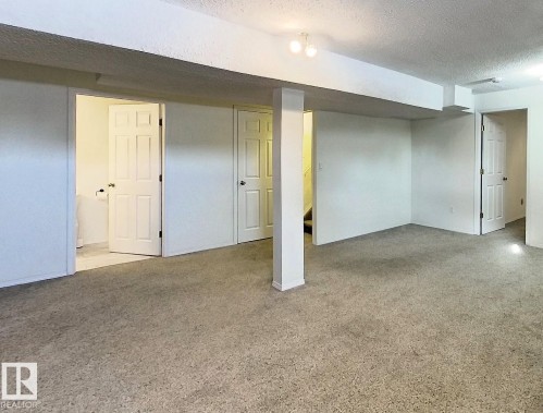 Finished basement with a textured ceiling and light carpet - 1102 55 Street, Edson, AB - Indoor