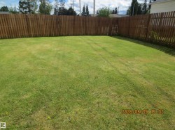 Expansive green lawn with a perimeter wood fence providing enclosure - 