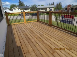 Spacious wooden deck featuring a natural wood finish, dark balusters, and sturdy wooden railings with decorative post caps - 