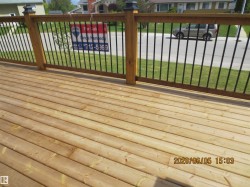 Expansive wood-finish decking featuring a natural wood railing with black metal balusters - 