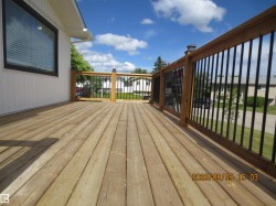 Spacious outdoor deck featuring natural wood planking and a perimeter railing with black vertical balusters - 