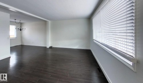 Empty room with suspended lighting and dark wood-type flooring - 1102 55 Street, Edson, AB - Indoor Photo Showing Other Room