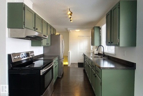 Kitchen with green cabinets, stainless steel range with electric stovetop, dark countertops, and dark wood finished floors - 1102 55 Street, Edson, AB - Indoor Photo Showing Kitchen With Upgraded Kitchen