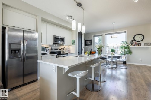 Kitchen featuring stainless steel appliances, backsplash, decorative light fixtures, a center island with sink, and a breakfast bar area - 1710 Keene Crescent. Sw, Edmonton, AB - Indoor Photo Showing Kitchen With Stainless Steel Kitchen With Upgraded Kitchen