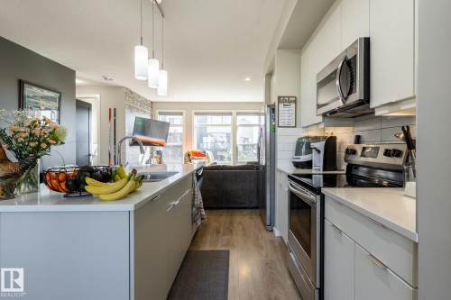 Kitchen with modern cabinets, open floor plan, stainless steel appliances, light wood-style flooring, and decorative light fixtures - 1710 Keene Crescent. Sw, Edmonton, AB - Indoor Photo Showing Kitchen With Double Sink With Upgraded Kitchen