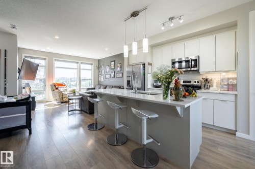 Kitchen with open floor plan, hanging light fixtures, an island with sink, white cabinets, and a breakfast bar - 1710 Keene Crescent. Sw, Edmonton, AB - Indoor Photo Showing Kitchen With Upgraded Kitchen