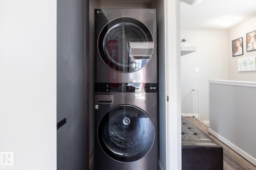 Laundry area featuring stacked washer / dryer, wood finished floors, and a textured ceiling - 1710 Keene Crescent. Sw, Edmonton, AB - Indoor Photo Showing Laundry Room