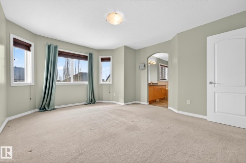 Unfurnished bedroom featuring arched walkways, carpet flooring, and ensuite bath - 152 Rue Marquet, Beaumont, AB -  With Exterior