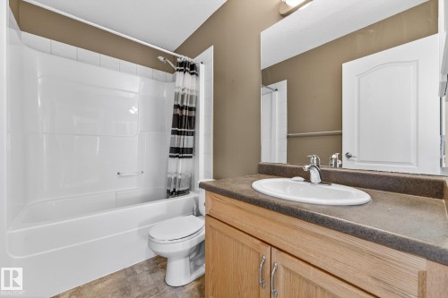 Bathroom with vanity, shower / bath combo with shower curtain, and stone finish flooring - 152 Rue Marquet, Beaumont, AB - Indoor Photo Showing Bathroom