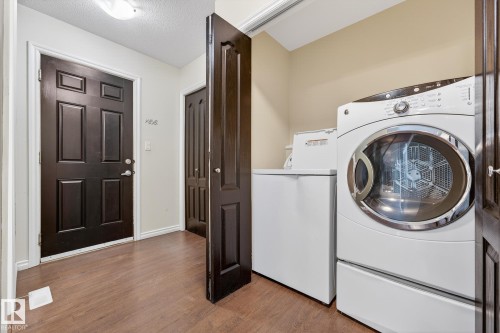 Laundry area with dark wood-type flooring, independent washer and dryer, and a textured ceiling - 152 Rue Marquet, Beaumont, AB - Indoor Photo Showing Laundry Room