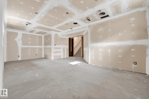 Unfurnished living room with concrete flooring and stairway - 152 Rue Marquet, Beaumont, AB - Indoor Photo Showing Other Room