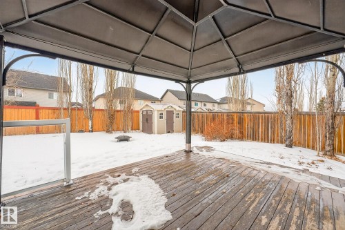 Snow covered deck featuring a storage unit, a fenced backyard, a residential view, and an outdoor fire pit - 152 Rue Marquet, Beaumont, AB - Outdoor With Deck Patio Veranda