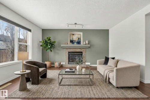 Living area with wood finished floors, a tile fireplace, and a textured ceiling - 152 Rue Marquet, Beaumont, AB - Indoor Photo Showing Living Room With Fireplace